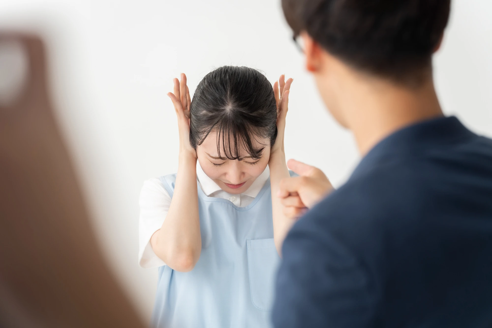 両耳に手を当てて耳を塞ぐ女性