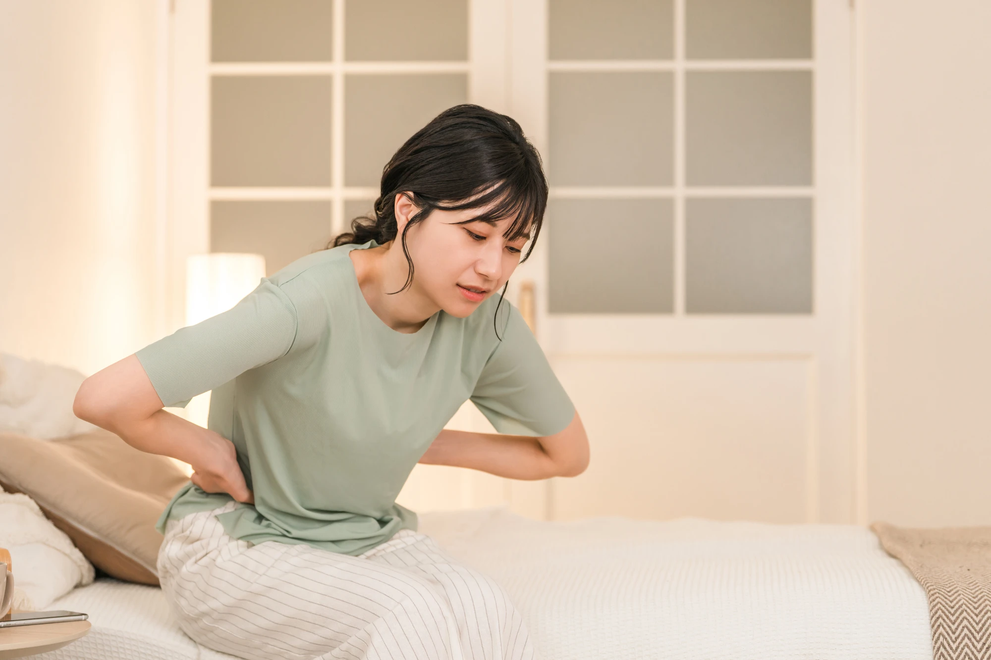 腰を押さえて苦しそうな女性
