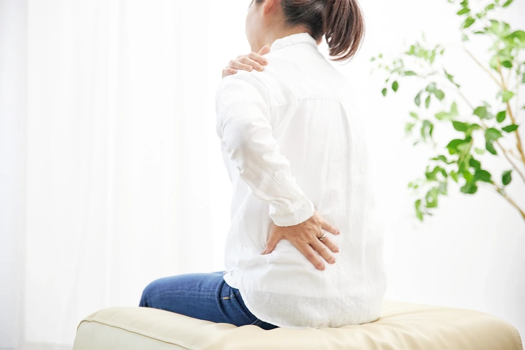 腰と肩を押さえる女性